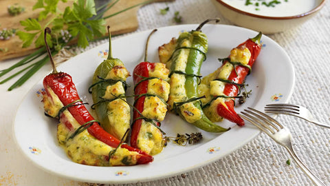 Gefüllte Minos Pfefferoni scharf mit cremiger Käsefüllung, gebacken und serviert mit frischen Kräutern, begleitet von einer Schale Joghurtsauce.