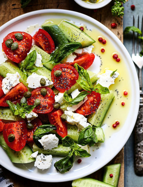 Frischer griechischer Salat mit Tomaten, Gurken, Feta und Basilikum, verfeinert mit Minos Nativem Olivenöl Extra.