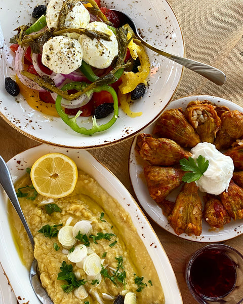 Griechischer Salat mit Olivenöl, serviert mit gefüllten Zucchiniblüten, Bohnenmus und einem frischen Bauernsalat mit Minos Natives Olivenöl Extra – die perfekte Mischung mediterraner Aromen