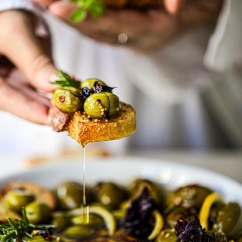 Griechische Oliven in hochwertigem Olivenöl, serviert mit Brot und Kräutern